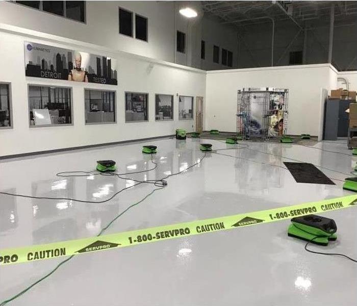 SERVPRO caution tape surrounding the puddles in a large commercial warehouse area